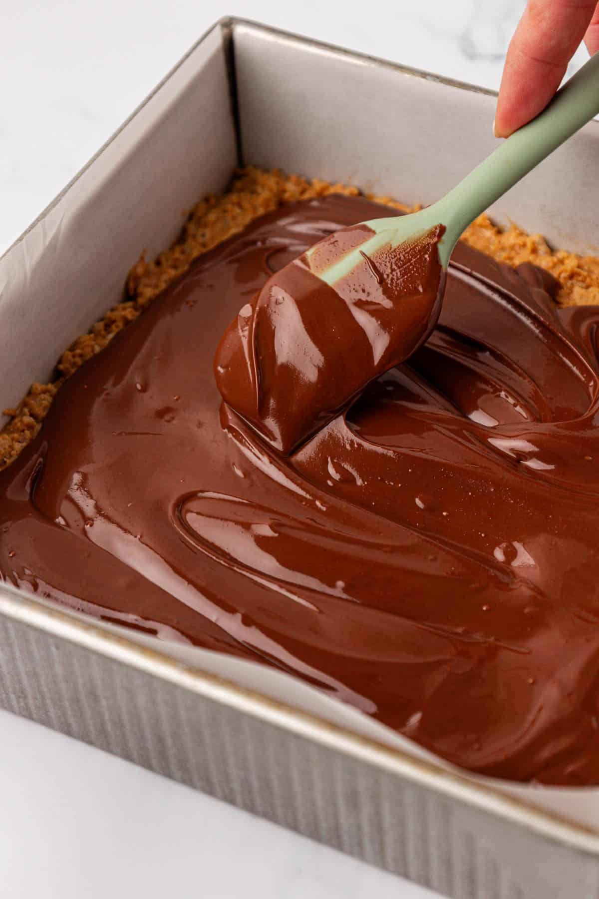 smoothing the melted chocolate over the rice krispies