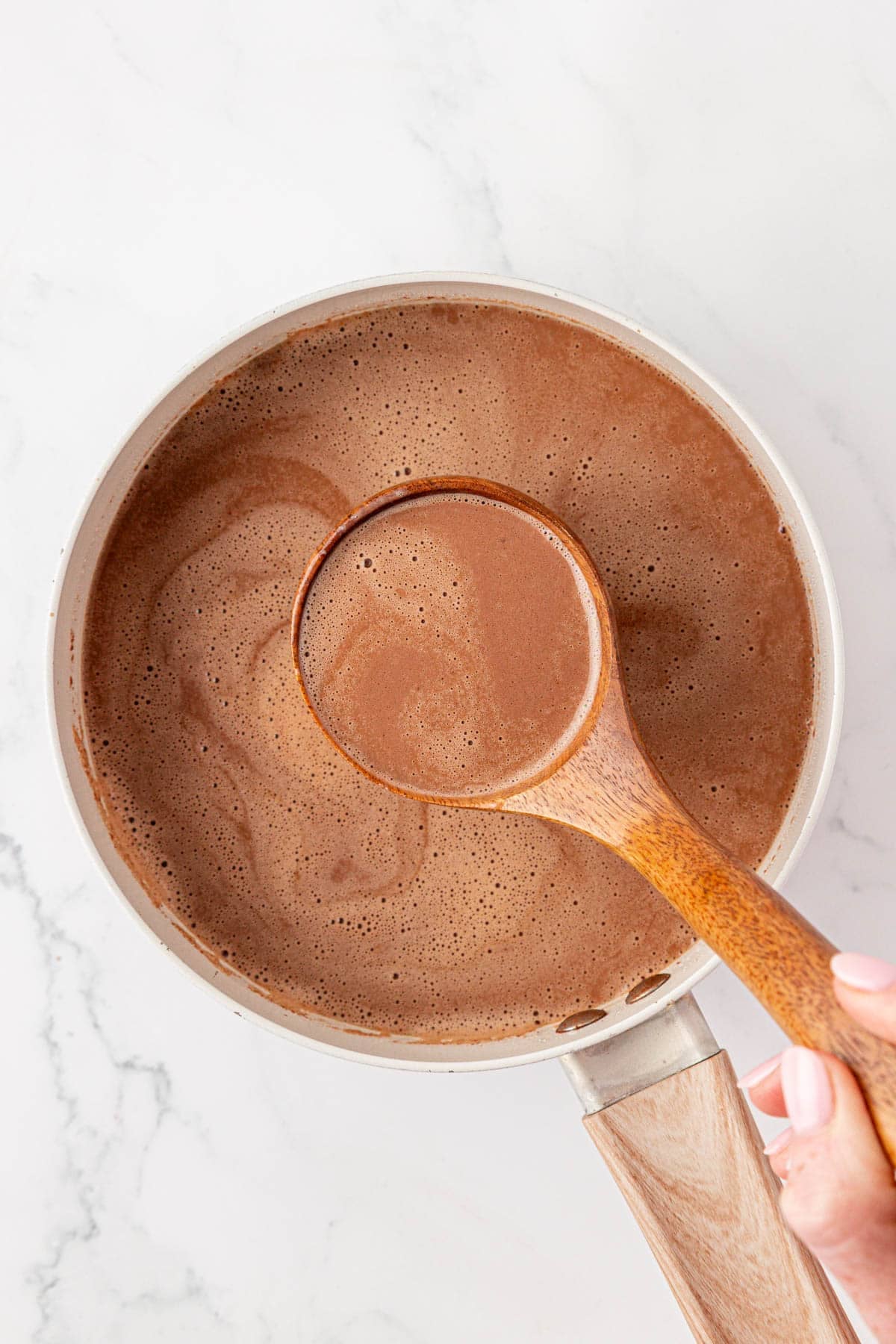 a ladle with hot chocolate over a pot