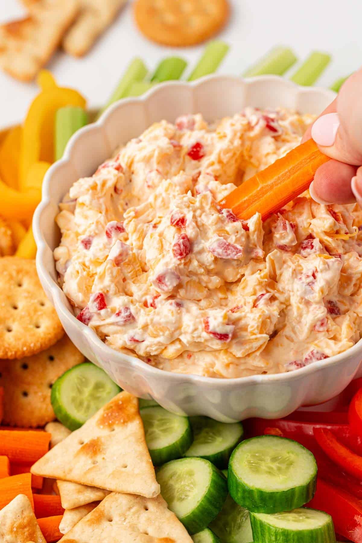 dipping a carrot into pimento cheese dip