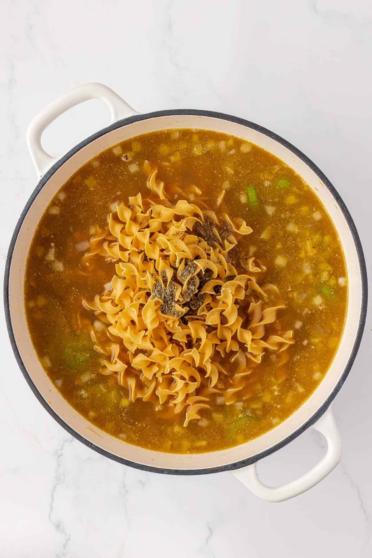 adding the egg noodles and more spices to the pot