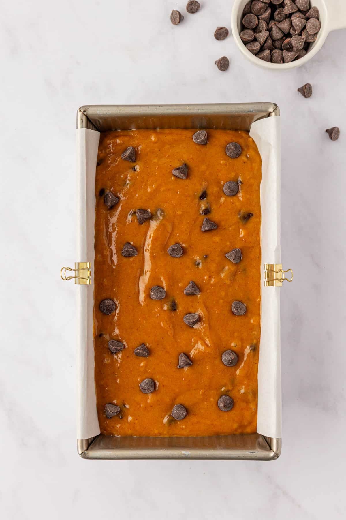 pumpkin bread batter in a loaf pan topped with chocolate chips