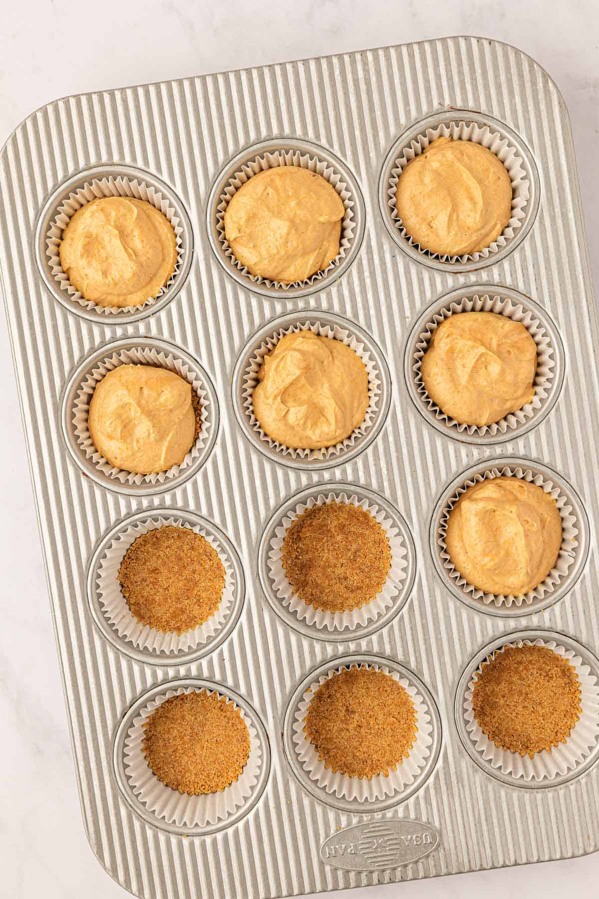 filling the muffin tin with pumpkin cheesecake filling