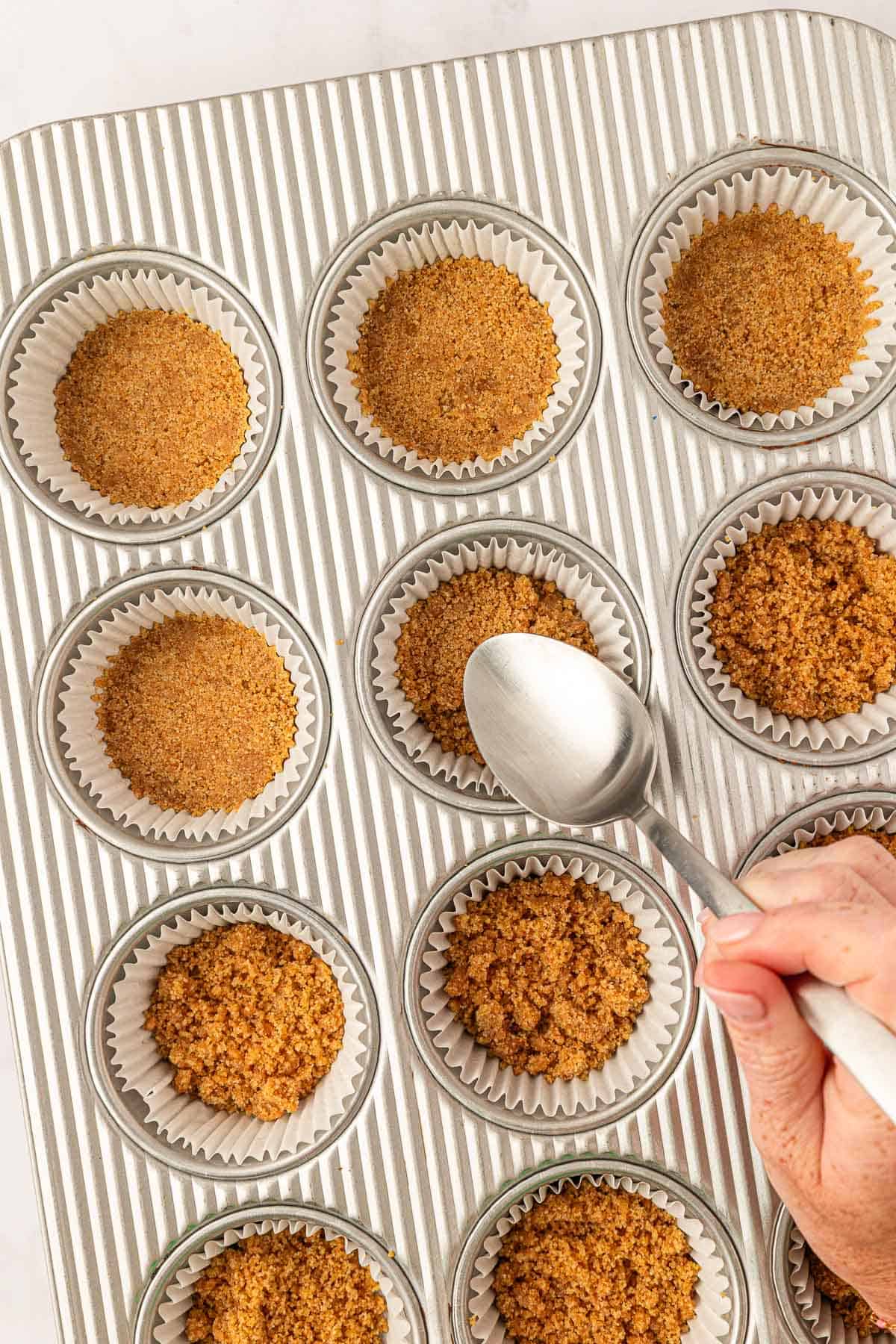 graham cracker crust pressed down into lined muffin tins