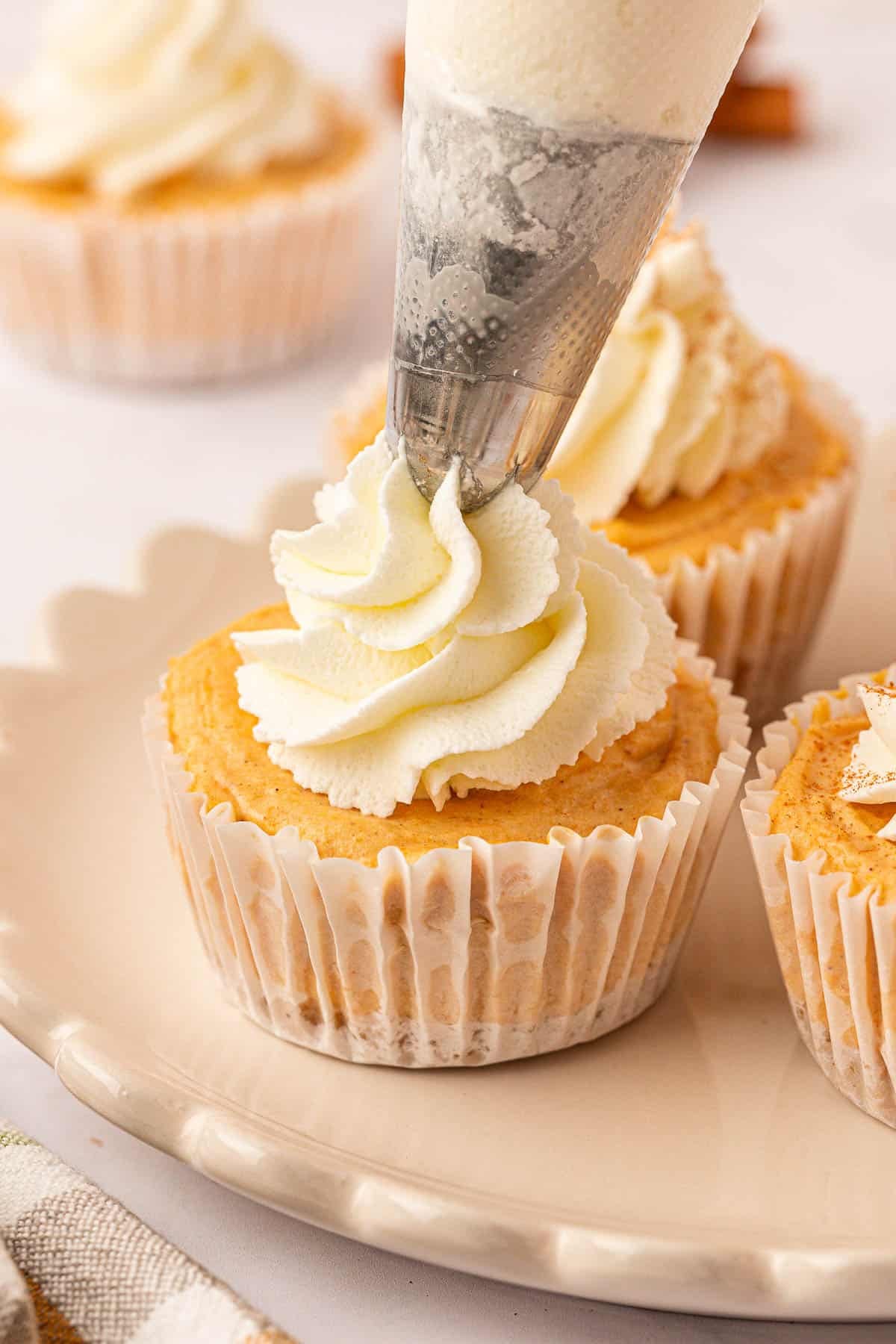 piping whipped cream onto a mini pumpkin cheesecake