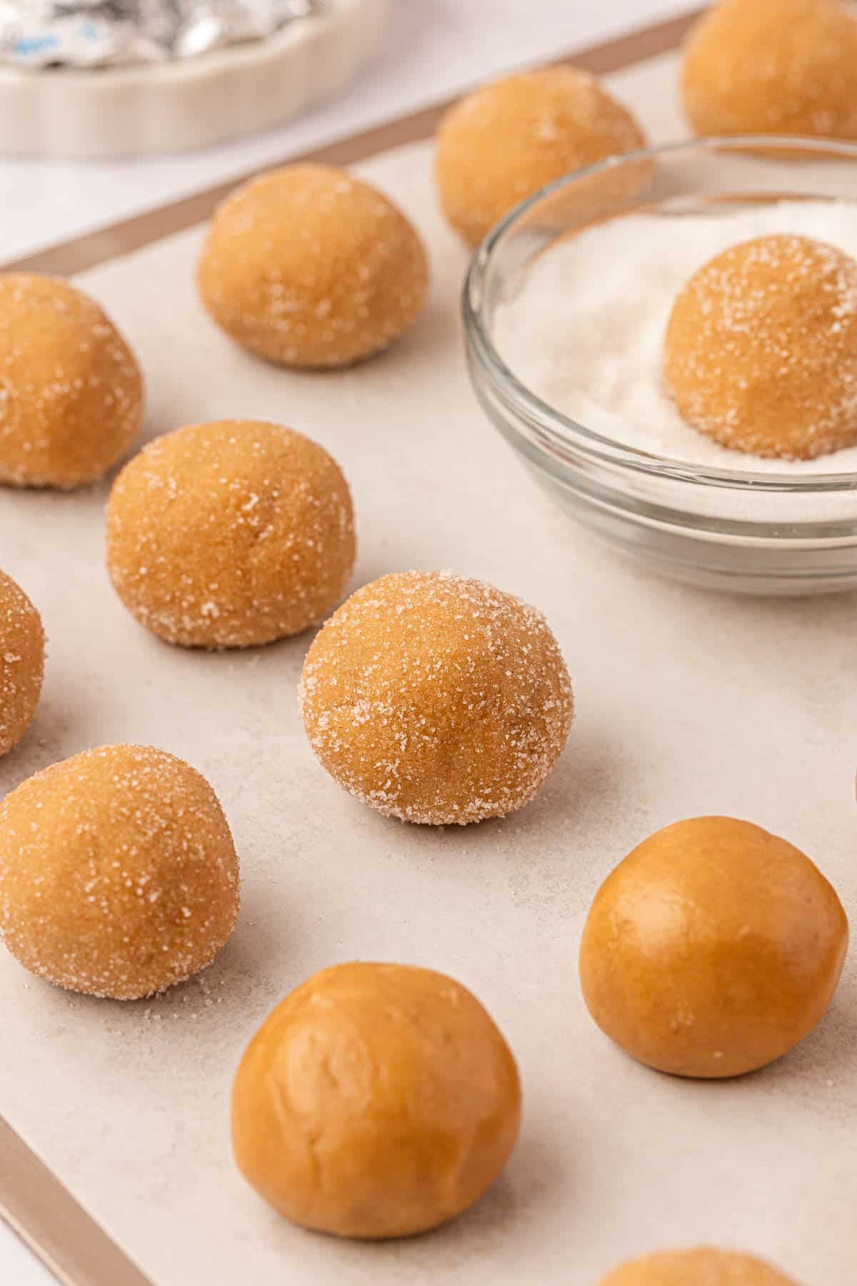 sugar coated peanut butter cookie dough balls on a baking sheet