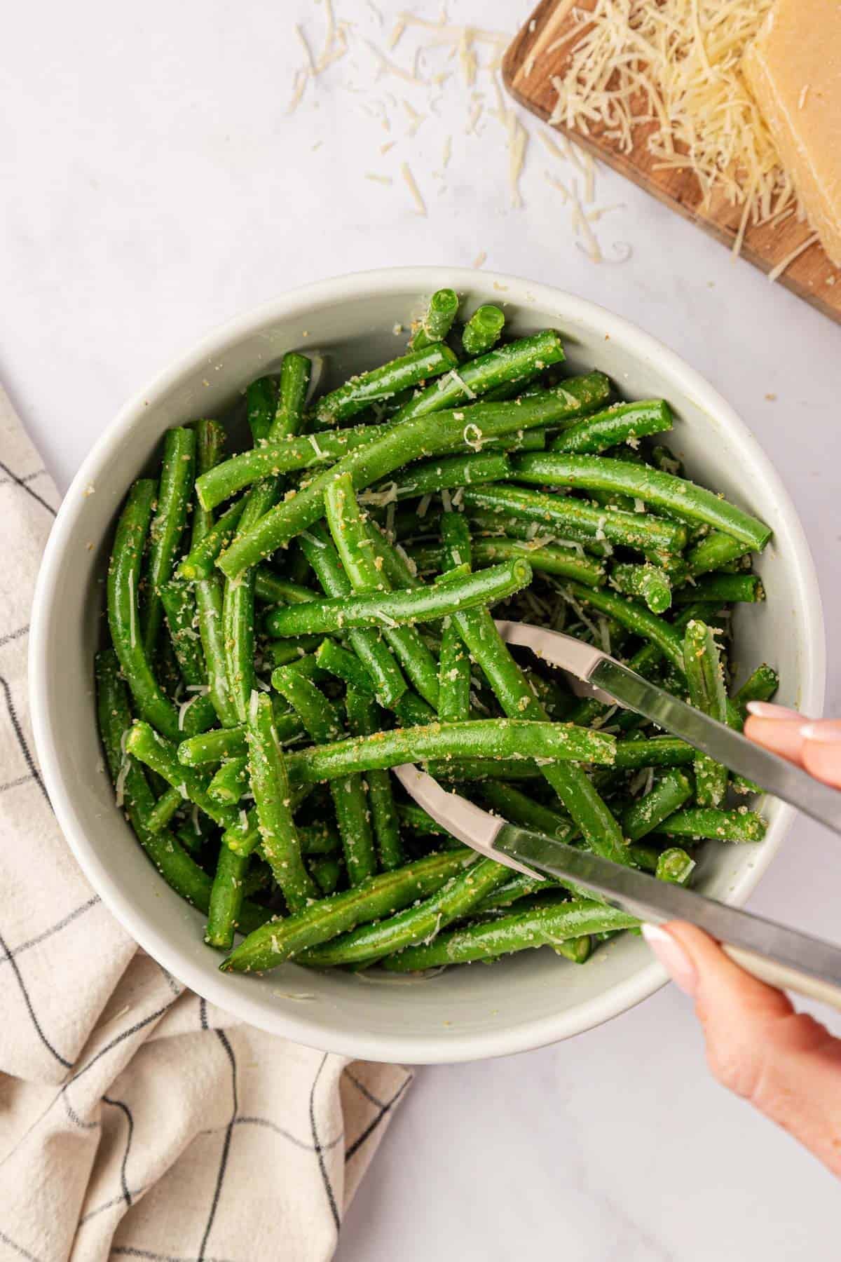 tossing the green beans with the parmesan, oil, and spices